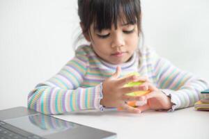 asiatisches kleines süßes mädchen, das rubiks würfel in ihren händen hält. Rubik's Cube ist ein Spiel, das die Intelligenz von Kindern steigert. foto