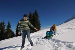 familie, die spaß auf frischem schnee im winterurlaub hat foto