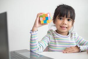 asiatisches kleines süßes mädchen, das rubiks würfel in ihren händen hält. Rubik's Cube ist ein Spiel, das die Intelligenz von Kindern steigert. foto