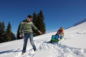 familie, die spaß auf frischem schnee im winterurlaub hat foto