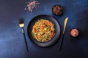 Frischer Salat aus geschnittenen dünnen Karotten- und Zucchinistreifen auf Betongrund foto