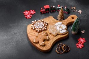 elemente von weihnachtsschmuck, süßigkeiten und lebkuchen auf einem holzschneidebrett foto