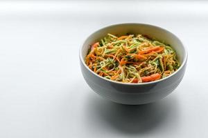 Frischer Salat aus geschnittenen dünnen Karotten- und Zucchinistreifen auf Betongrund foto