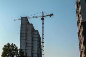 Baukran gegen den blauen Himmel. die Immobilienwirtschaft. Ein Kran verwendet Hebezeuge auf einer Baustelle. foto
