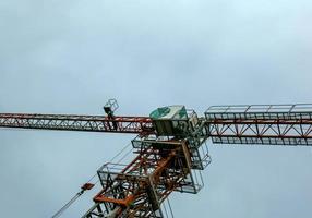 Baukran gegen den blauen Himmel. die Immobilienbranche. Ein Kran verwendet Hebezeuge auf einer Baustelle. foto