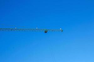 Baukran gegen den blauen Himmel. die Immobilienbranche. Ein Kran verwendet Hebezeuge auf einer Baustelle. foto