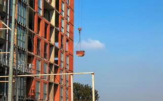 Baukran gegen den blauen Himmel. die Immobilienbranche. Ein Kran verwendet Hebezeuge auf einer Baustelle. foto