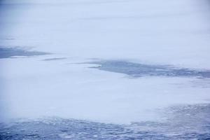 Winterhintergrund der eisigen Oberfläche des Flusses. Textur von Eis mit Schnee bedeckt. foto