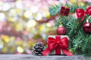 nahaufnahme der handgefertigten geschenkbox mit rotem band und tannenzapfen auf holztisch für weihnachts- oder neujahrsdekorationshintergrund foto