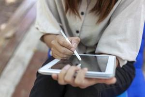 Hand eines Mädchens, das einen digitalen Tablet-Stift hält, um etwas auf das digitale Tablet zu schreiben. foto