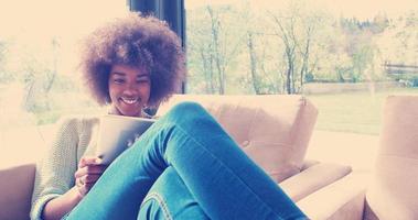 Afroamerikanerin zu Hause mit digitalem Tablet foto