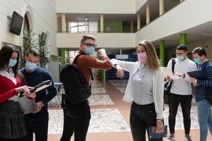 studenten begrüßen den neuen normalen coronavirus-händedruck und ellbogenstoß foto