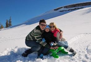 familie, die spaß auf frischem schnee im winterurlaub hat foto