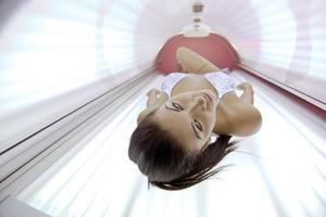 schöne junge Frau im Solarium bräunen foto