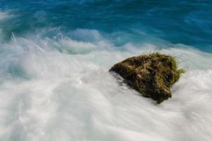 einzelner Stein im wilden Fluss foto