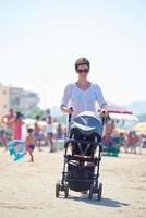 Mutter am Strand spazieren und Kinderwagen schieben foto