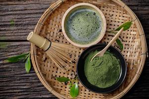 Japanisches Bio-Matcha-Grünteepulver in Schüssel mit Schneebesen und grünem Teeblatt auf Holzhintergrund, Bio-Produkt aus der Natur für gesundes mit traditionellem Stil foto