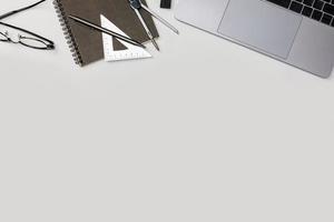 Draufsicht-Arbeitsbereichsmodell des Architekturprojekts mit Laptop-Computer, Architekturprojektplan, Ingenieurwerkzeugen und Büromaterial auf weißem Schreibtisch leerer Raum für Ihren Text isoliert auf Weiß foto