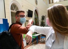 studenten begrüßen den neuen normalen coronavirus-händedruck und ellbogenstoß foto