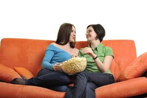 freundinnen, die popcorn essen und zu hause fernsehen foto