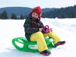 glücklicher kleiner junge hat spaß im winterurlaub auf frischem schnee foto