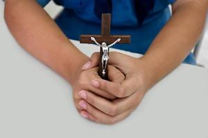 Holzkreuz mit einer Statue von Jesus, der von seinem Arm gekreuzigt wurde und die Hände des Gebets auf einem weißen Tisch in der Kirche hält, weicher und selektiver Fokus. foto