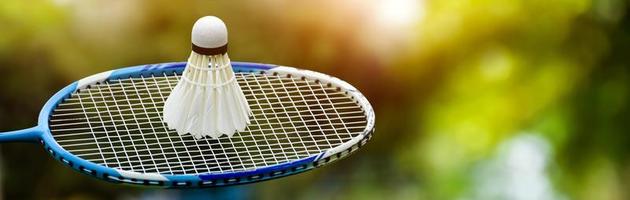 Badmintonschläger und Badmintonfederball vor bewölktem und blauem Hintergrund, Badmintonspielkonzept im Freien. selektiver Fokus auf Schläger. foto