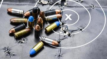 9-mm-Pistolenkugeln und Kugelschalen auf Schießscheibenpapier, weicher und selektiver Fokus. foto