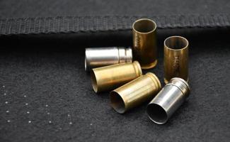 9-mm-Pistolenkugeln und Kugelschalen auf schwarzem Lederhintergrund, weicher und selektiver Fokus. foto