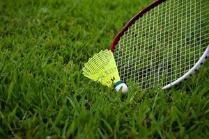 Badminton-Ausrüstungen im Freien weiße und gelbe Federbälle aus Kunststoff und Badmintonschläger, auf Grasrasen, weicher und selektiver Fokus auf Federbälle im Freien, Badminton-Spielkonzept foto