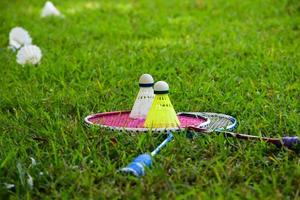 Badminton-Ausrüstungen im Freien weiße und gelbe Federbälle aus Kunststoff und Badmintonschläger, auf Grasrasen, weicher und selektiver Fokus auf Federbälle im Freien, Badminton-Spielkonzept foto