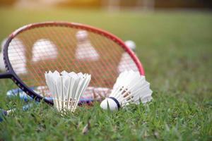 Badminton-Ausrüstungen im Freien weiße und gelbe Federbälle aus Kunststoff und Badmintonschläger, auf Grasrasen, weicher und selektiver Fokus auf Federbälle im Freien, Badminton-Spielkonzept foto