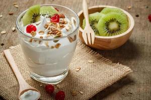 hausgemachter Joghurt oder Sauerrahm in einem Glas mit Kiwi - auf dem Holztisch foto