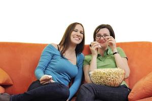 freundinnen, die popcorn essen und zu hause fernsehen foto