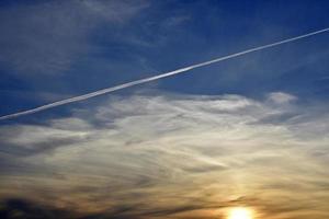 ein flugzeug, das in den blauen himmel und in die wolken fliegt. ein weißer Kondensstreifen aus einem Flugzeug am Sommerhimmel. foto