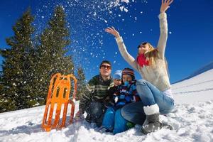 familie, die spaß auf frischem schnee im winterurlaub hat foto