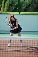 junge frau spielt tennisspiel im freien foto