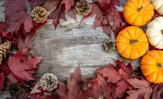 festliche herbstdekoration aus kürbissen, kiefern und blättern auf einem hölzernen hintergrund. konzept des erntedankfestes oder halloweens. flach gelegte herbstkomposition mit kopierraum. foto