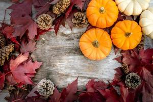 festliche herbstdekoration aus kürbissen, kiefern und blättern auf einem hölzernen hintergrund. konzept des erntedankfestes oder halloweens. flach gelegte herbstkomposition mit kopierraum. foto