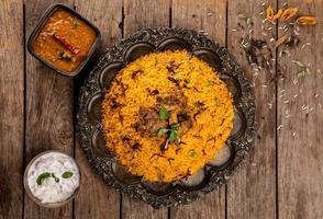Hammel-Biryani aus stark gewürztem Reis und Gewürzen, mariniertes Fleisch, gekocht mit eigenen Säften und aromatischen indischen Gewürzen, serviert mit Brinjal-Sauce und Zwiebel-Raitha als Beilage. foto