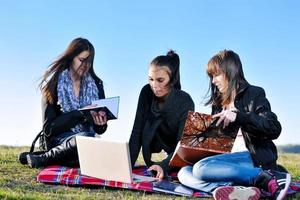 Gruppe von Teenagern, die im Freien am Laptop arbeiten foto