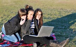 Gruppe von Teenagern, die im Freien am Laptop arbeiten foto