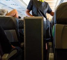 eine Winkelaufnahme einer Stewardess, die etwas an Passagiere weitergibt. foto