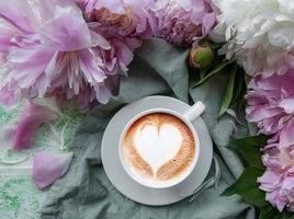 rosa Pfingstrosenblüten und Tasse Kaffee foto