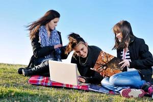 Gruppe von Teenagern, die im Freien am Laptop arbeiten foto