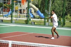 junger Mann spielt Tennis im Freien foto