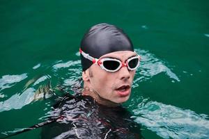 Triathlon-Athlet, der auf dem See schwimmt und einen Neoprenanzug trägt foto