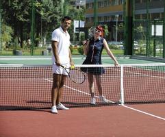 glückliches junges paar spielt tennisspiel im freien foto