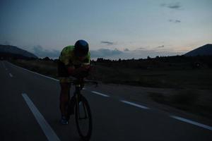 Triathlon-Athlet, der nachts Fahrrad fährt foto