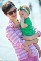 Mama und Baby am Strand haben Spaß foto